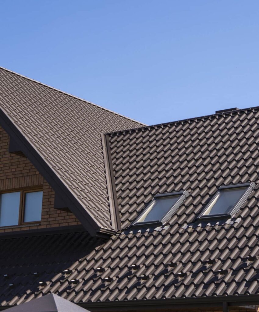 Toiture en tuiles avec fenêtres de toit (Velux), ciel bleu en arrière-plan.